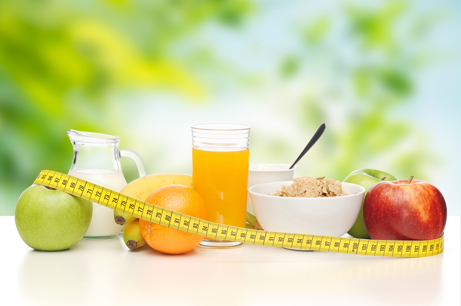 Morgenmad med et målbånd rundt om frugterne, juice, mælk og cornflakes