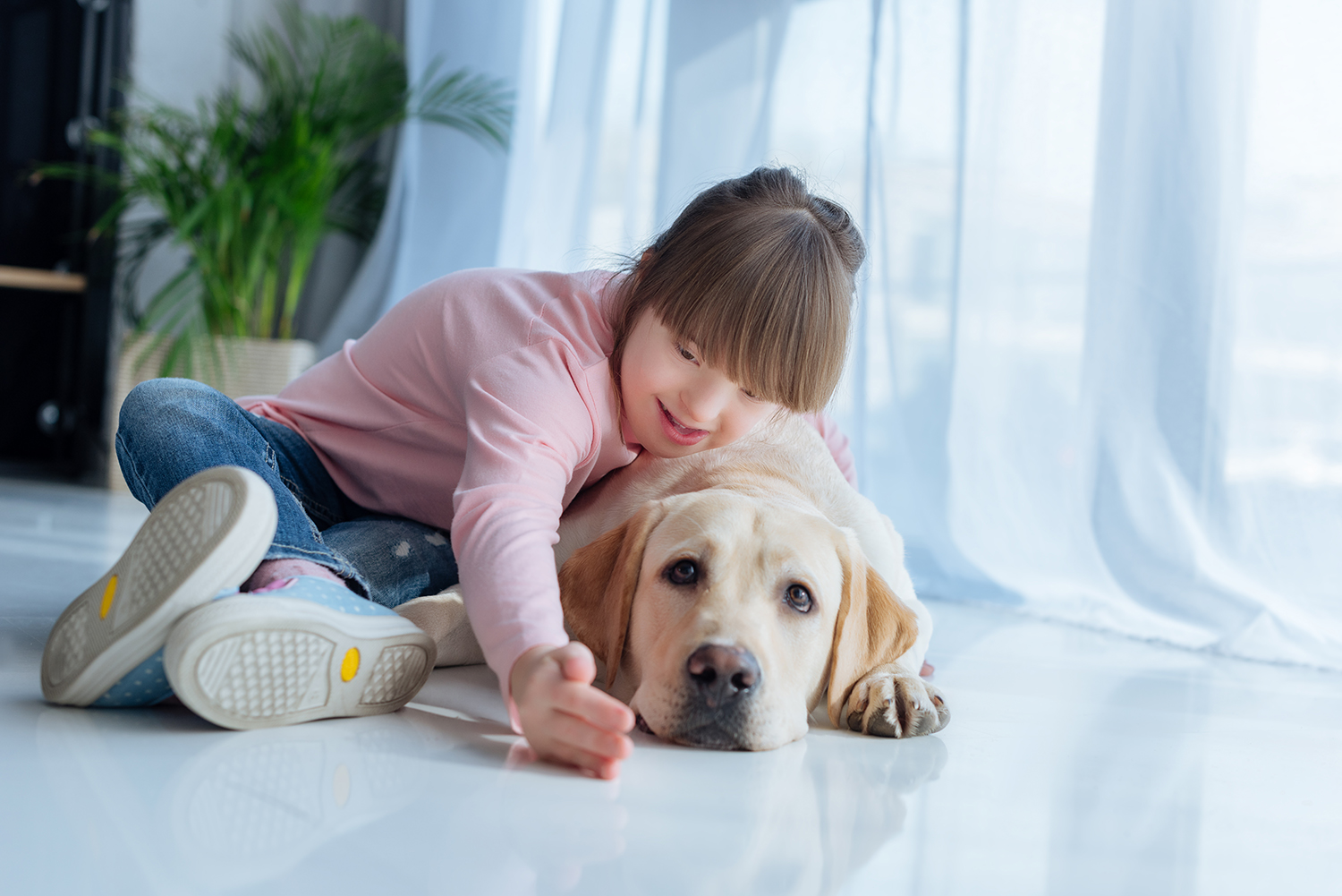 Handicappet pige der ligger på gulvet sammen med hendes hund