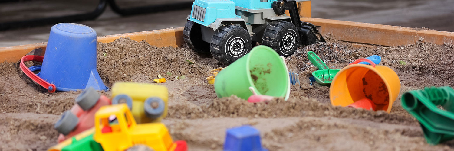 Sandkasse der er fyldt med farvestrålende legesager